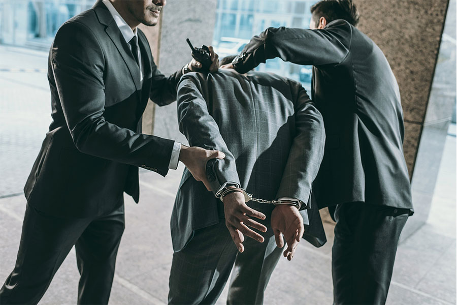 Two men handcuffing a man