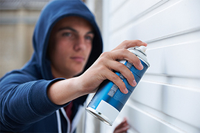 Teenage Boy Spray Painting Garage Door