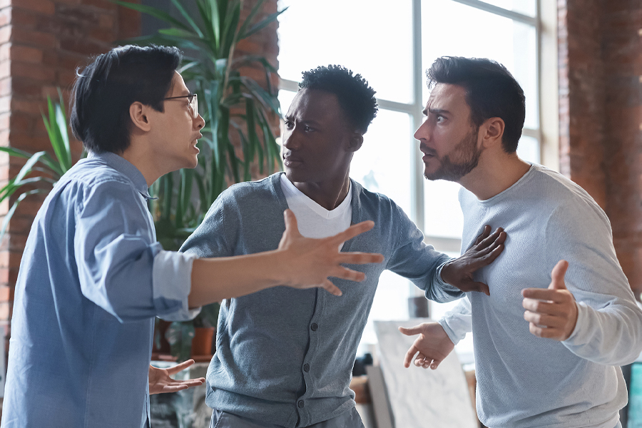 Office conflict. Angry multiracial young men fighting at the workplace, afro guy standing between them.