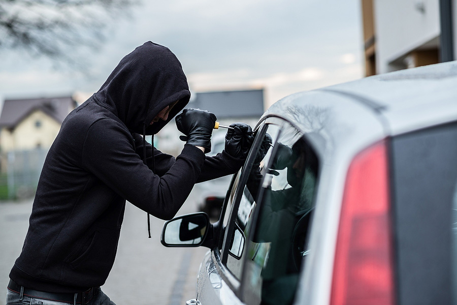 robber using a tool to break into a car