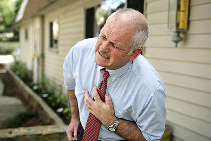 A mature businessman doubled over clutching his chest. He appears to be having a heart attack.