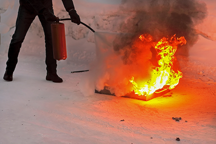 A man extinguishes an open fire with a fire extinguisher.
