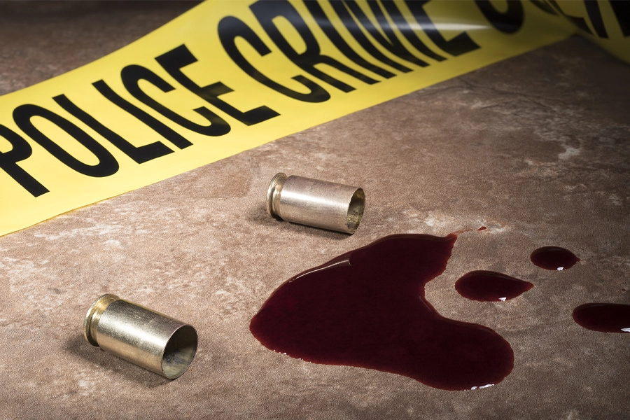 Blood next to empty pistol shells and police line tape on the floor