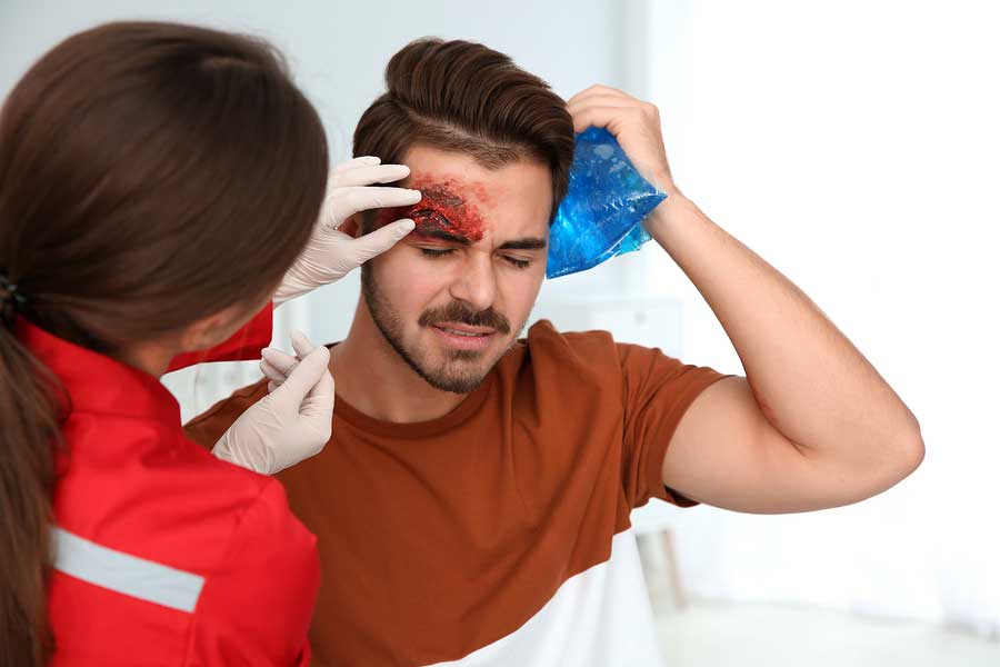 Nurse examining young man's head injury in clinic First aid