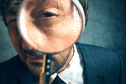 Enlarged eye of inspector looking through magnifying glass