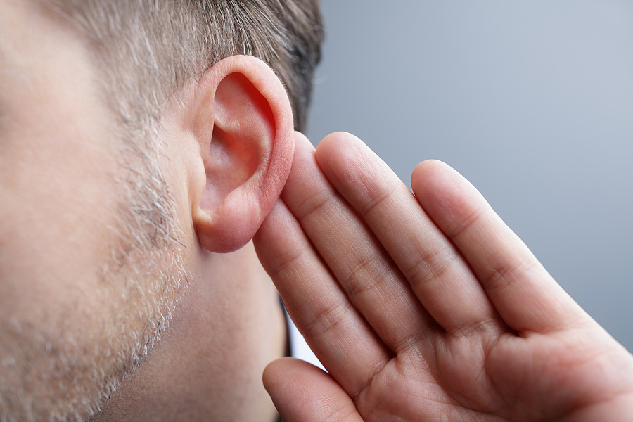 Man with his hand behind his ear listening for a sound.