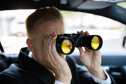 Private Detective Sitting In Car Looking Through Binocular
