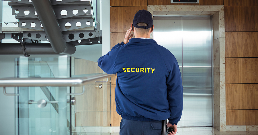 Rear view of security guard waiting for lift while standing in office building
